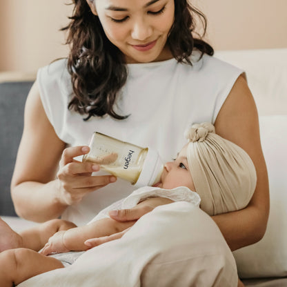 Mum feeding her baby with a 150ml Hegen PPSU feeding bottle with a white cap.